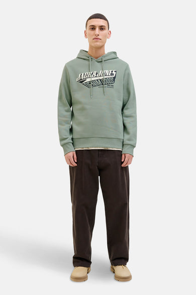 Pull-over vert de capuche d'ORIGINALS BY JACK & JONES, avec un logo imprimé sur la poitrine et des pantalons marron et des chaussures.