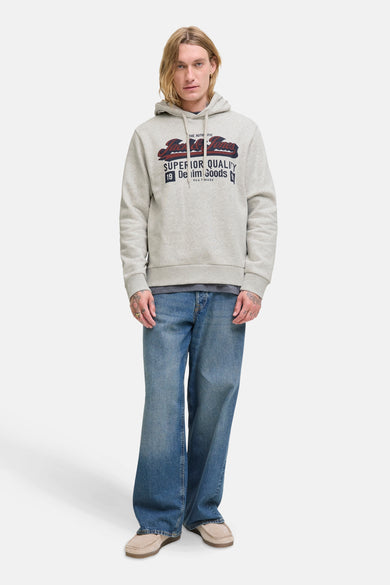Witte sweater met kap van ORIGINALS BY JACK & JONES, met grafische print op de borst, gecombineerd met blauwe jeans en beige schoenen.