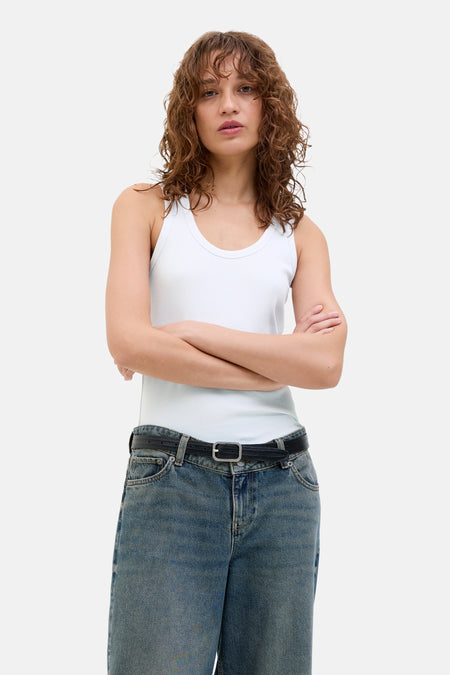 Witte geribbelde tanktop van JJXX, gestyled met blauwe jeans en een zwarte riem.
