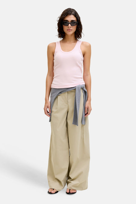 Roze geribbelde tanktop van JJXX, gestyled met zonnebril, een grijze trui om de taille en een beige wijde broek.