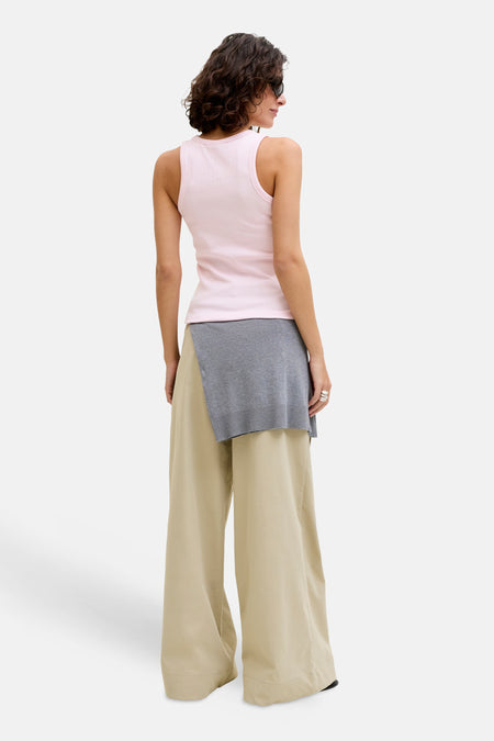 Haut côtelé rose de JJXX, porté avec un pull gris à la taille et un pantalon beige ample.