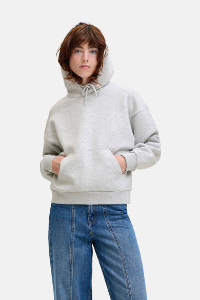Pull gris à capuche de JJXX Studio, avec des manches longues et un kangourou, associé à des jeans bleus.
