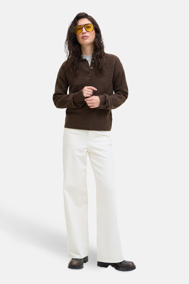 Pull marron de JJXX, avec des manches longues, une fermeture à boutons et porté avec un pantalon blanc et des chaussures marron.