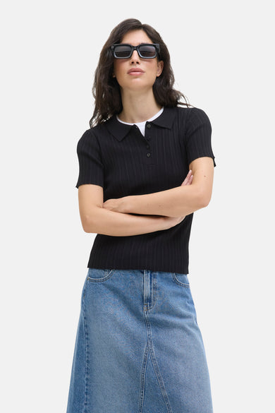 Pull noir de JJXX, porté avec une jupe en cuir et un masque de soleil noir.