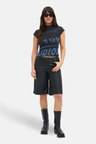 Blauw JJXX T-shirt met korte mouwen van JJXX, met een blauwe '1993' print en gedragen met zwarte shorts en laarzen.
