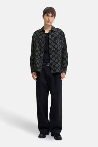 Chemise noire à manches longues de CORE BY JACK & JONES, avec un motif géométrique frappant et portée avec une chemise noire et un pantalon large.