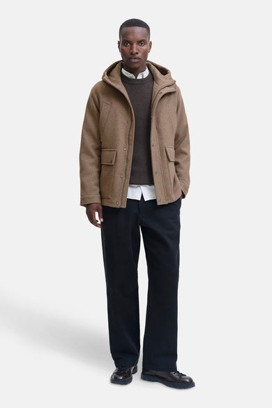 Beige lange jas van PREMIUM by JACK & JONES, gedragen over een bruine trui en een wit overhemd.