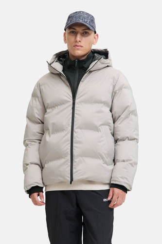 Ecru korte jas van CORE BY JACK & JONES, met capuchon, zwarte ritssluiting en zwarte trainingsbroek.
