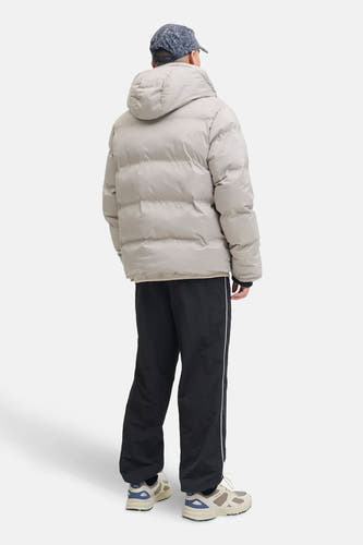 Ecru korte jas van CORE BY JACK & JONES, met capuchon, gedragen met een zwarte broek met witte streep.
