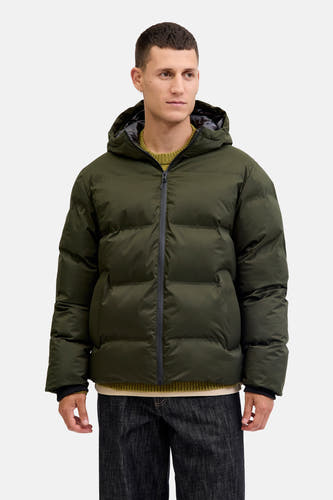 Korte groene jas van CORE BY JACK & JONES, met capuchon, gedragen over een groene trui en donkere jeans.

