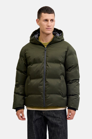 Manteau vert court de CORE BY JACK & JONES, avec capuche, porté sur un pull vert et des jeans foncés.