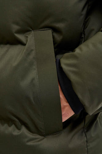 Korte groene jas van CORE BY JACK & JONES, met hand in zak en zwarte mouwboord zichtbaar.