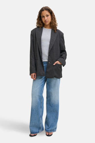 Grijze blazer van JJXX, gedragen met een grijs shirt en wijde jeans.