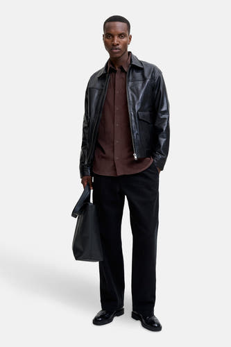 Bruin, lang mouwen hemd van PREMIUM BLUE by JACK & JONES, gedragen onder een zwart leren jack met een zwarte tas.
