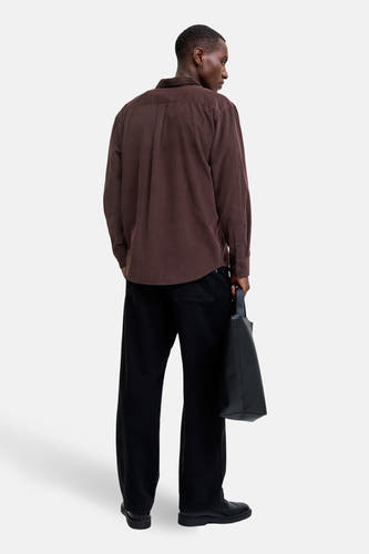 Bruin, corduroy overhemd met lange mouwen van PREMIUM BLUE by JACK & JONES, gezien van achteren, gecombineerd met zwarte pantalon en een zwarte tas.
