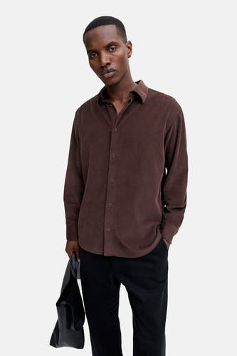 Bruin, corduroy overhemd met lange mouwen van PREMIUM BLUE by JACK & JONES, gedragen met zwarte broek en leren tas.