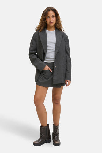 Grijze skort van JJXX, gecombineerd met een grijze top, een grijs jasje en bruine laarzen.
