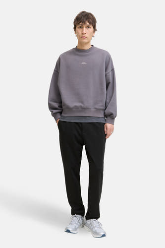 Zwarte broek van JACK & JONES JEANS INTELLIGENCE, gecombineerd met een grijze trui en witte sneakers.