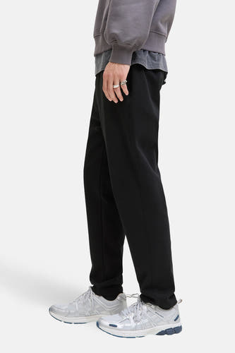 Zwarte broek van JACK & JONES JEANS INTELLIGENCE, met zilveren sneakers en grijze trui, zijaanzicht.