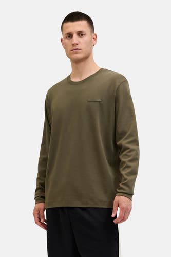 Gilet kaki de CORE BY JACK & JONES avec des manches longues et un détail sur la poitrine, porté avec un pantalon noir.