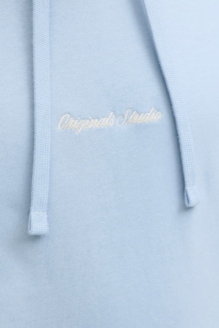 Pull en maille bleu clair à capuche de ORIGINALS BY JACK & JONES, avec broderie blanche 'Originals Studio' sur la poitrine et cordons de serrage.