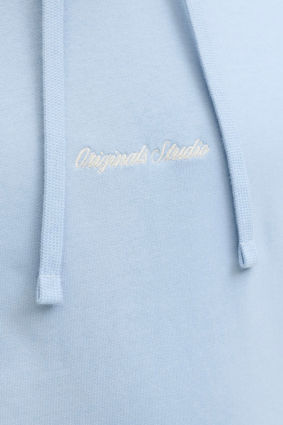 Pull en maille bleu clair à capuche de ORIGINALS BY JACK & JONES, avec broderie blanche 'Originals Studio' sur la poitrine et cordons de serrage.
