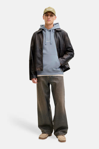 Blauwe sweater met kap van ORIGINALS BY JACK & JONES, gedragen met een leren jas, wijde broek en pet.