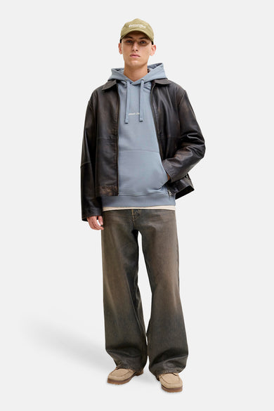 Blauwe sweater met kap van ORIGINALS BY JACK & JONES, gedragen met een leren jas, wijde broek en pet.