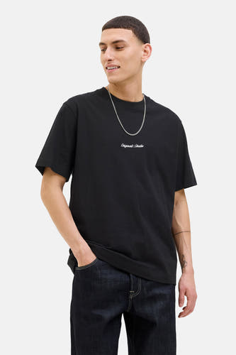 T-shirt noir à manches courtes d'ORIGINALS BY JACK & JONES, porté avec une chaîne en argent et des jeans bleu marine.