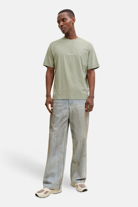 Groen T-shirt met korte mouwen van ORIGINALS BY JACK & JONES, gedragen met een losse jeans en crèmekleurige sneakers.