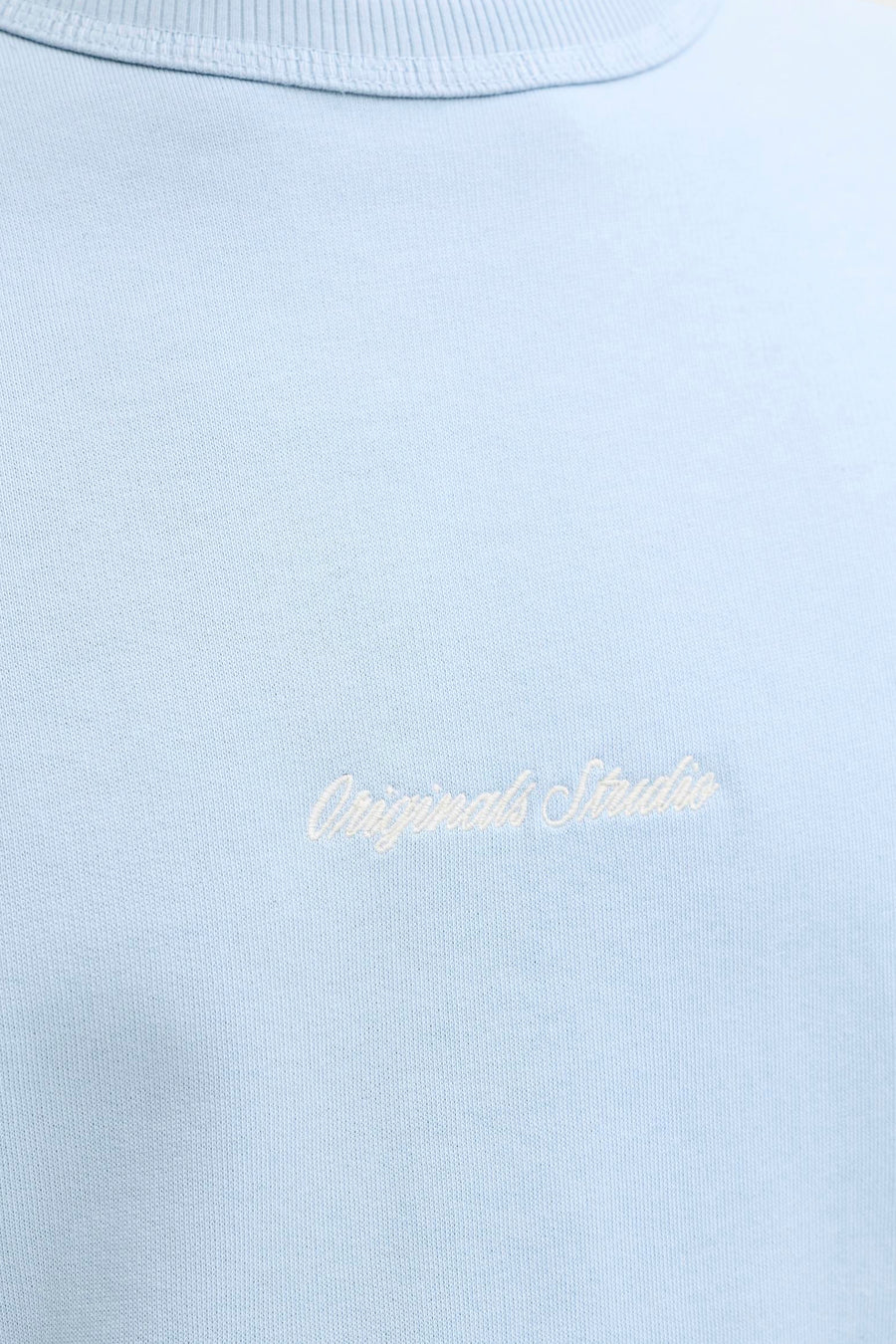 Lichtblauwe sweater met ronde hals van ORIGINALS BY JACK & JONES met witte 'Originals Studio' borduurtekst op de borst.