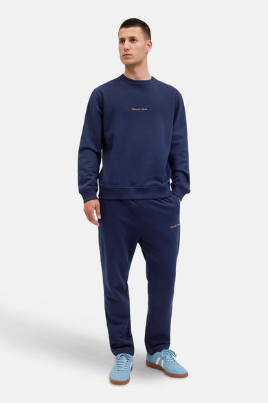 Blauwe sweater van ORIGINALS BY JACK & JONES, met lange mouwen en merknaam op de borst, gedragen met bijpassende joggingbroek en lichtblauwe sneakers.