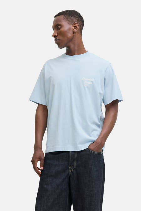 Blauw T-shirt met korte mouwen van ORIGINALS BY JACK & JONES, met witte tekstprint, gecombineerd met donkere jeans.

