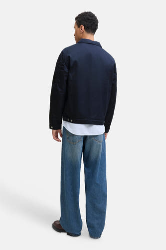 Korte blauwe jas van ORIGINALS BY JACK & JONES, gezien van achteren, gecombineerd met een wit overhemd en wijde jeans.