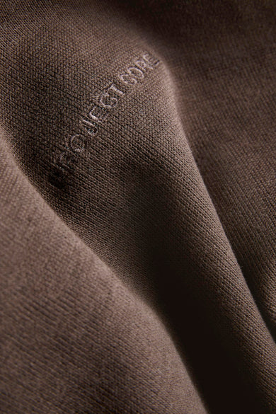 Bruine sweater van CORE BY JACK & JONES, close-up van de stof met een subtiel logo.