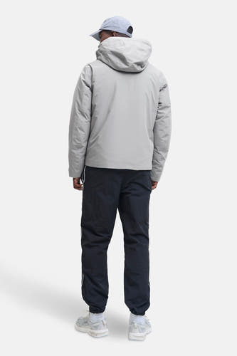 Korte grijze jas van CORE BY JACK & JONES, met capuchon, gecombineerd met een donkere broek en sneakers.