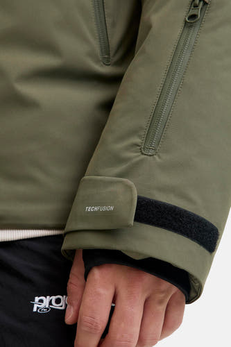 Veste courte verte de CORE BY JACK & JONES avec détail de manche : fermeture éclair verticale, texte 'TECHFUSION' et fermeture auto-agrippante.