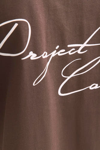 T-shirt brun à manches courtes de CORE BY JACK & JONES, avec une impression de texte blanche en police de caractères ondulée.