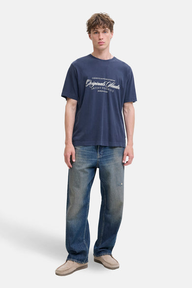 T-shirt bleu à manches courtes d'ORIGINALS BY JACK & JONES, avec une impression blanche, associé à des jeans et des chaussures.