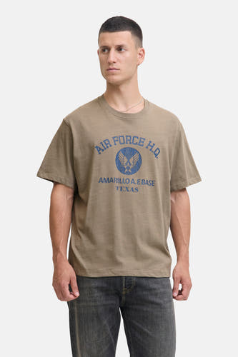 Kaki T-shirt met korte mouwen van PREMIUM BLUE by JACK & JONES, met blauwe print en gedragen met grijze jeans.
