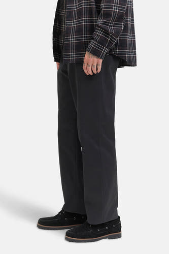 Jean noir chino de JACK & JONES JEANS INTELLIGENCE, porté avec un chemisier à carreaux et des bottes en cuir de mouton, dans une vue latérale.