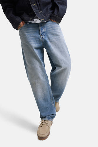 Jean en denim bleu avec des jambes larges de JACK & JONES JEANS INTELLIGENCE, avec un léger lavage et des chaussures beige.