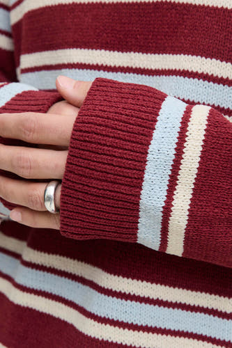 Pull à col V rouge d'ORIGINALS BY JACK & JONES, avec un motif rayé en rouge, bleu et beige et une bague argentée visible.