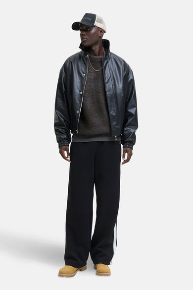 Sweat gris à col rond de CORE BY JACK & JONES, porté avec un manteau en cuir noir et une chaîne d'or.