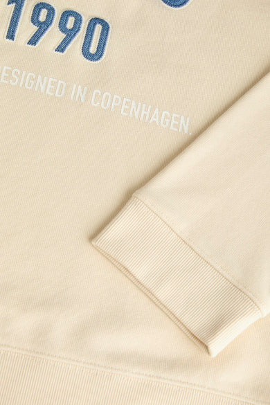 Beige sweater van ORIGINALS BY JACK & JONES, met '1990 ontworpen in Kopenhagen'-tekst en een geribbelde boord aan de mouwen.
