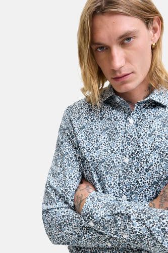 Chemise bleue à manches longues de PREMIUM by JACK & JONES, avec un motif floral et des bras croisés.