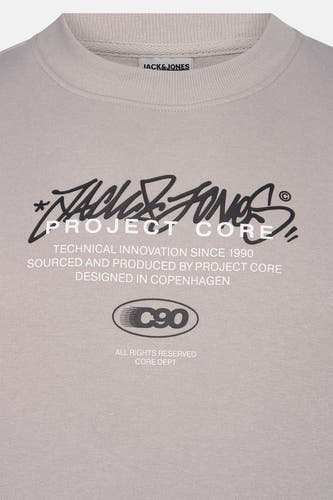Grijze sweater van CORE BY JACK & JONES, met zwarte en witte merklogo's en tekstprint op de voorkant.
