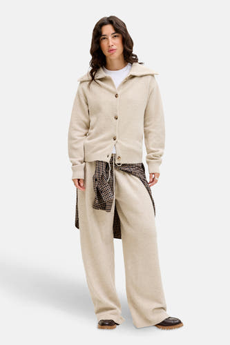 Beige cardigan van JJXX, met lange mouwen en een klassieke kraag, gecombineerd met een geruit overhemd.
