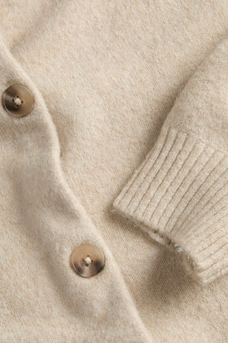 Veste beige de JJXX, avec fermeture à boutons et un bord de manche côtelé, en gros plan.