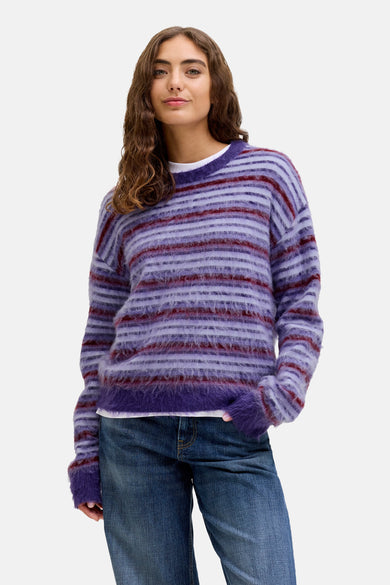 Pull rond col rond de XX XX JJ, avec des hor horales et porté avec des jeans larges et des chaussures marron.